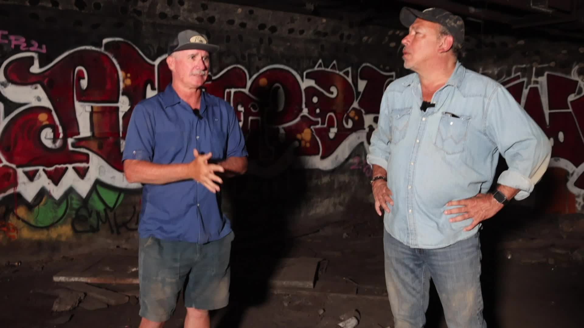 Chris Epting stands with guest inside a graffiti'd tunnel